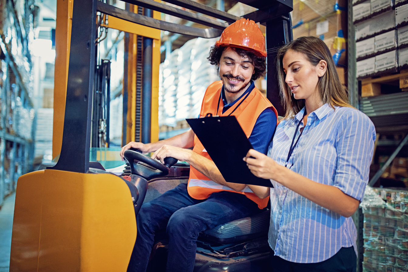 Manager is giving instructions to forklift operator in the warehouse